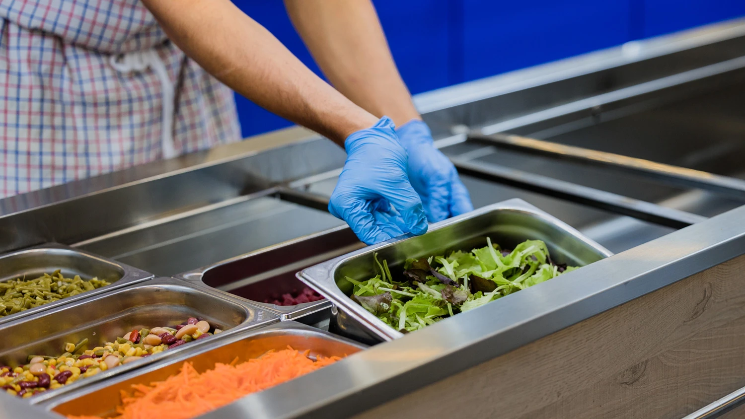 Jeune apprenti préparant un bac de salade pour un self-service.