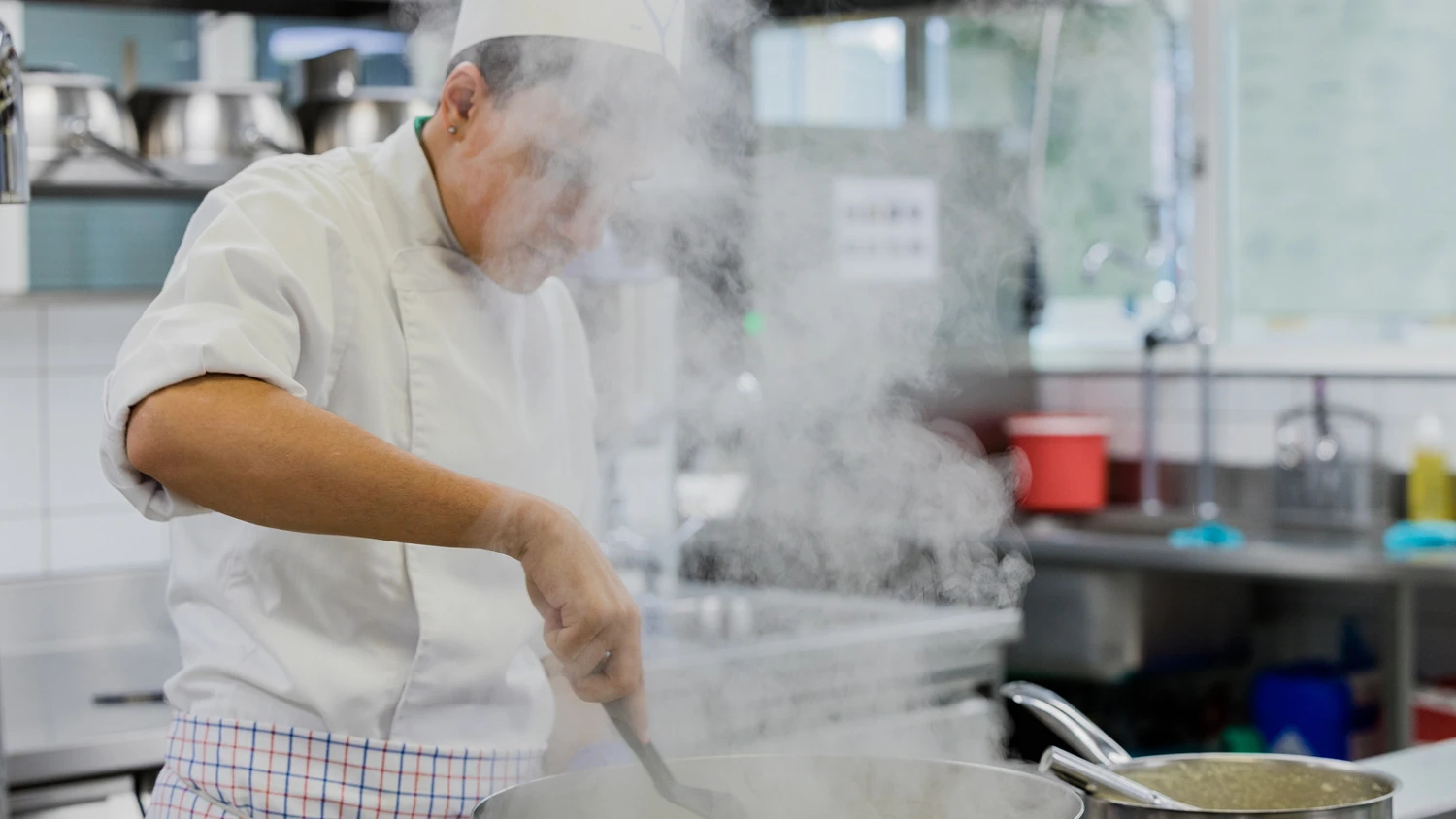 Jeune apprenti cuisinant dans une cuisine professionnelle.