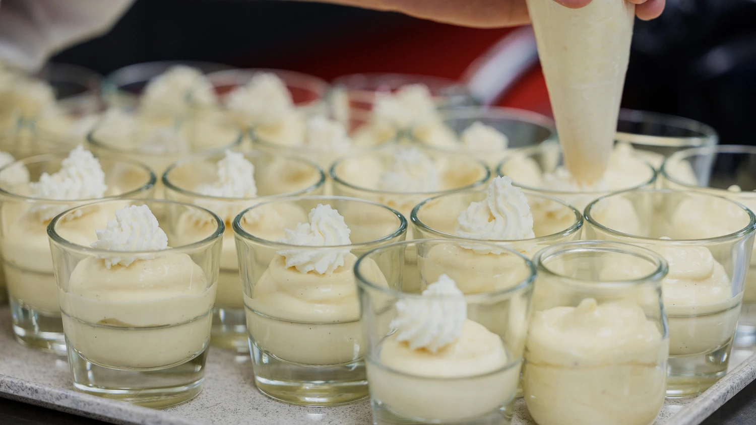 Jeune apprenti préparant des desserts dans des verrines.