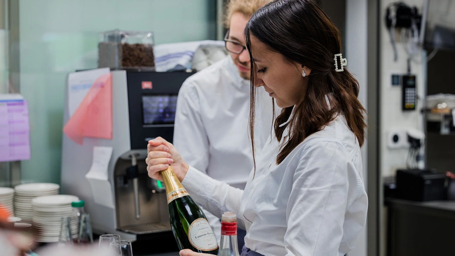 Jeune apprenti ouvrant une bouteille de champagne.