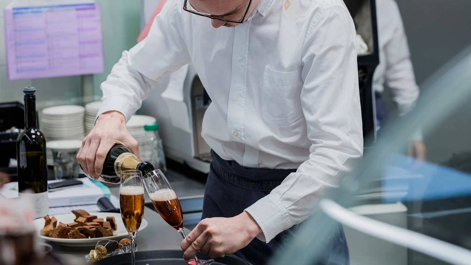 Jeune apprenti servant du champagne dans des coupes à champagne.