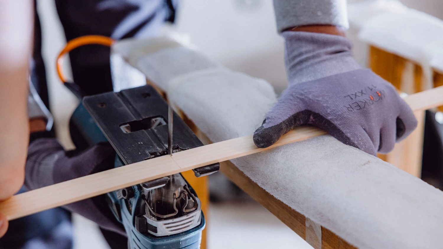 Jeune apprenti découpant une lamelle en bois à l'aide d'une machine.