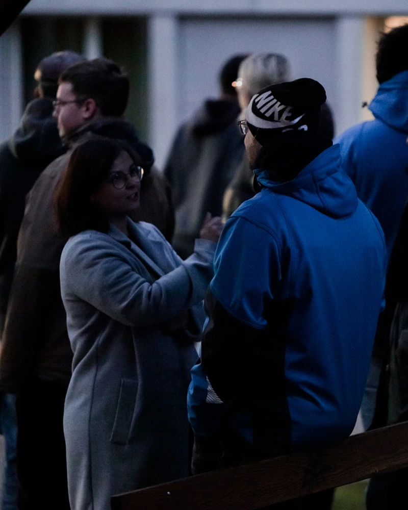 Deux personnes discutant à l'extérieur, un soir d'hiver.