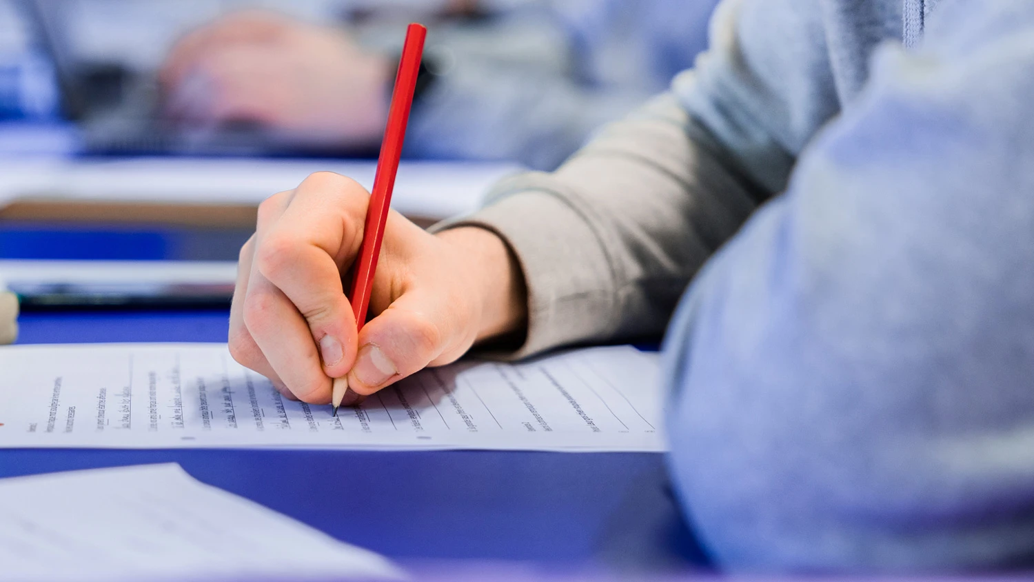 Jeune apprenti écrivant sur une feuille avec un crayon.