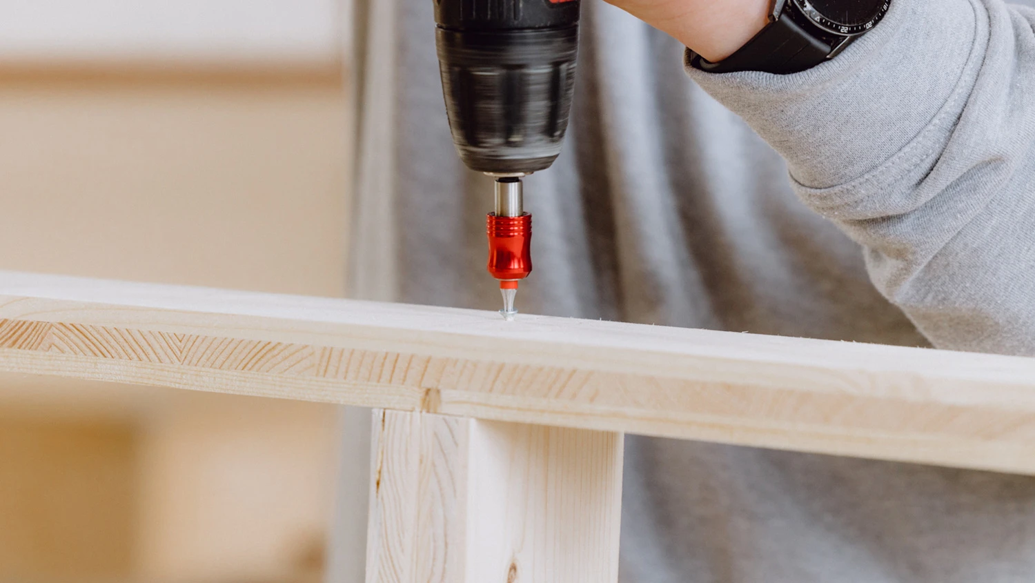 Jeune apprenti vissant deux planches de bois perpendiculairement.