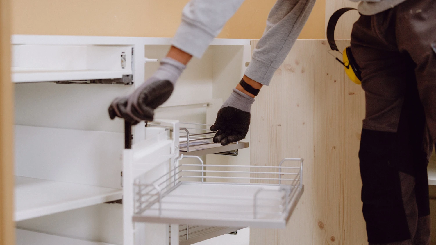 Jeune apprenti posant un tiroir en bois dans une cuisine en construction.