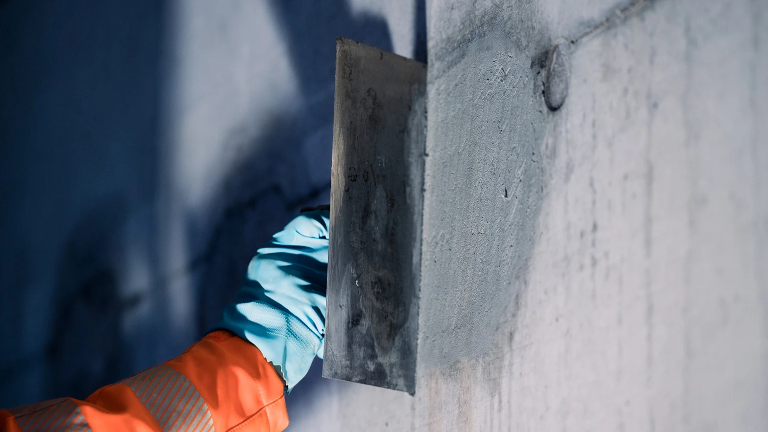 Jeune apprenti bouchant les joints d'un mur en béton.